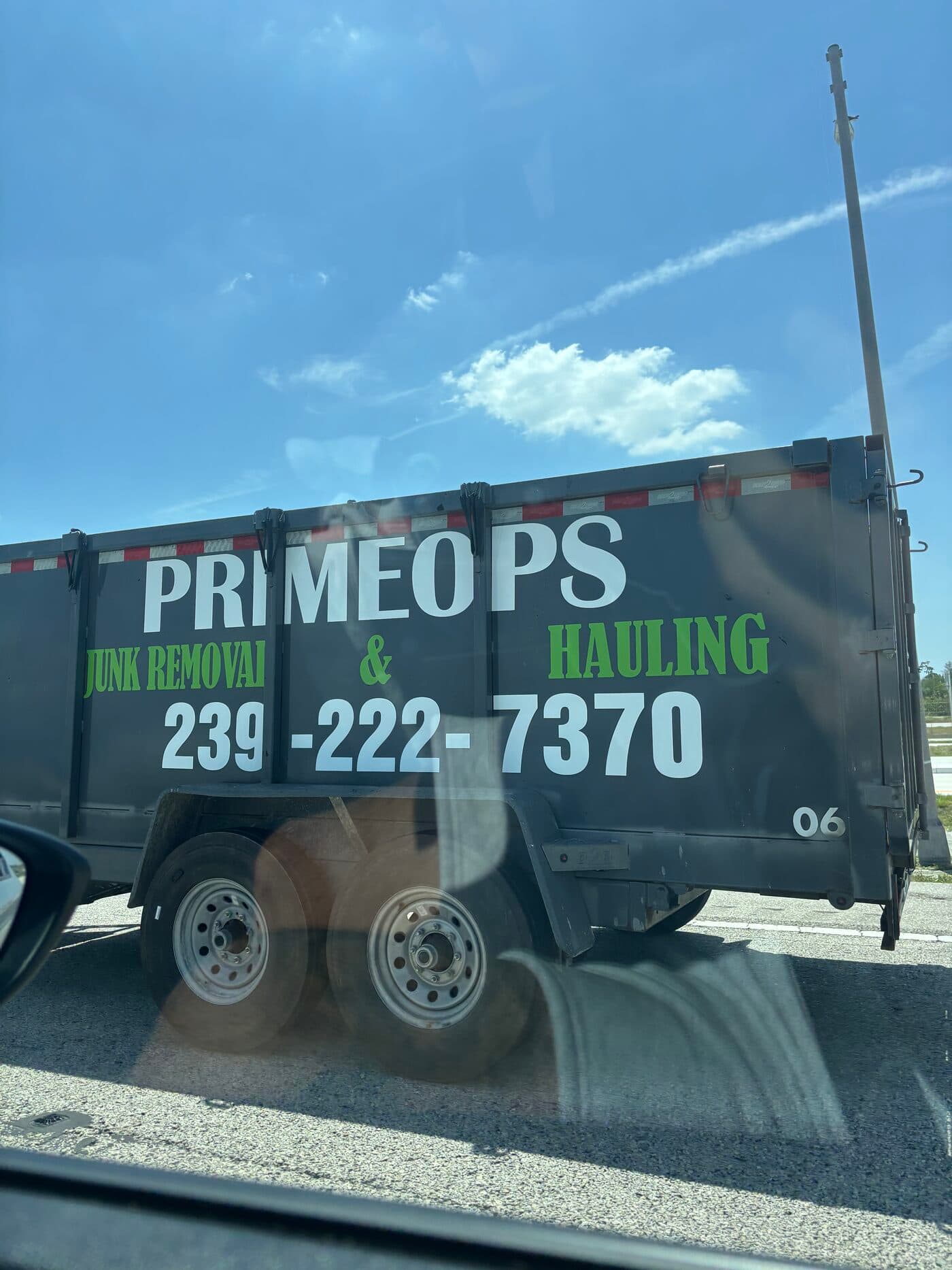 Prime Ops Hauling branded junk removal trailer on the road in Naples, FL